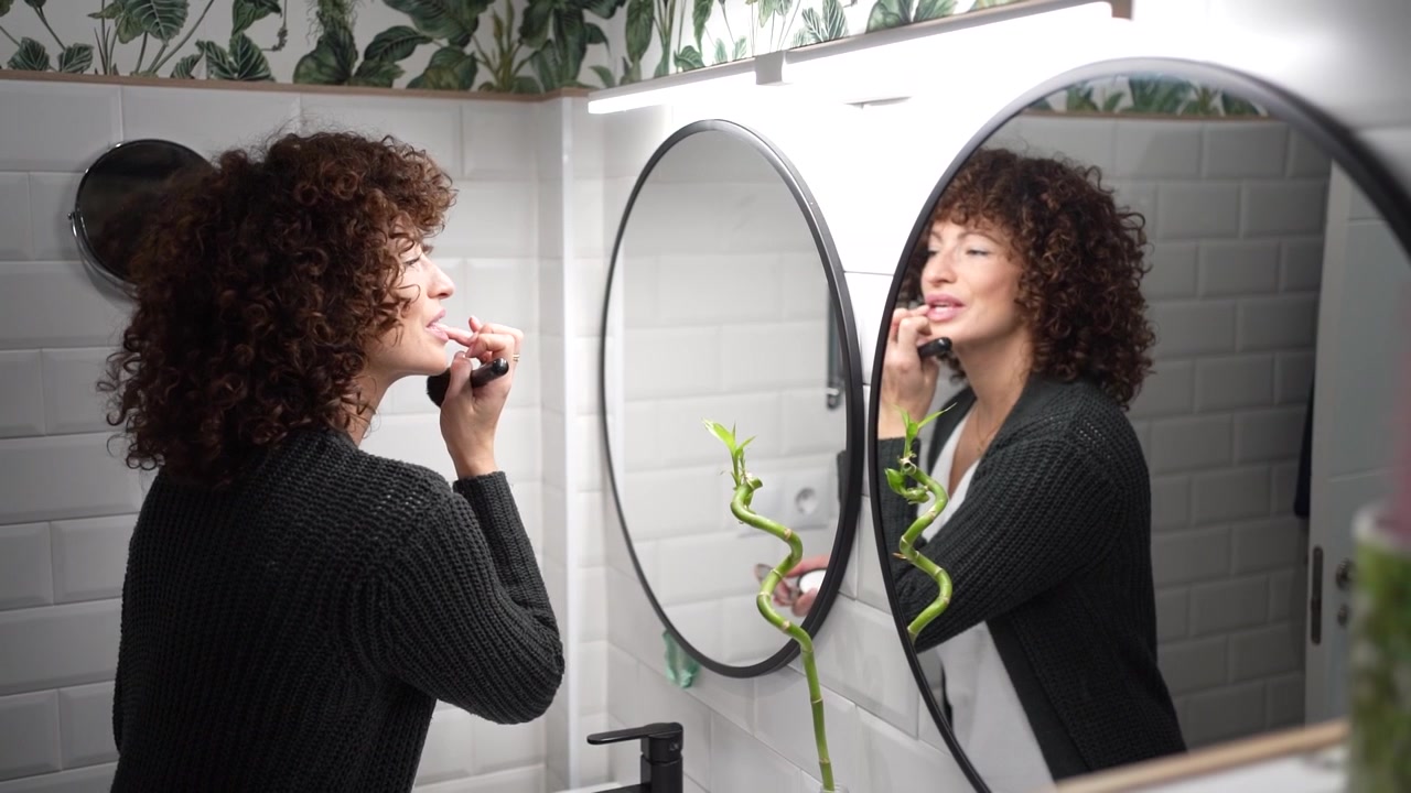 Una donna in un bagno elegante ammira il bellissimo riflesso di una pianta da interno.