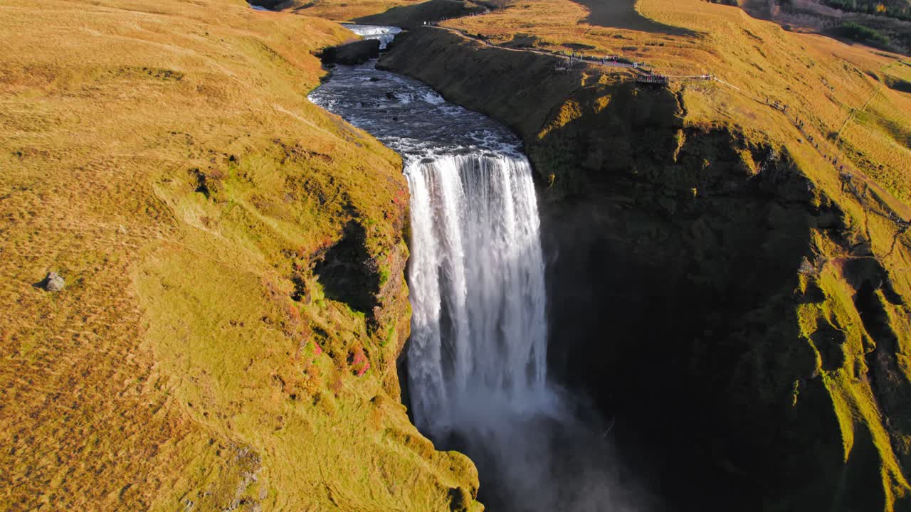 gran cascada famosa de skogafoss en islandia rodeada de follaje de musgo amarillo