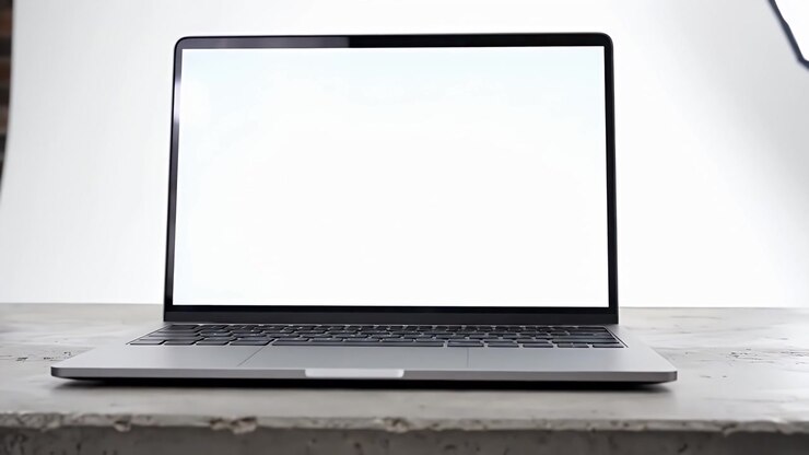 Moderner Laptop mit leerem weißem Bildschirm auf Betonschreibtisch