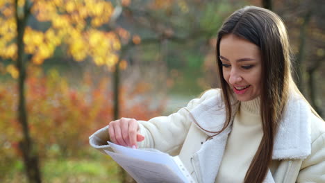 woman reading documents in autumn park