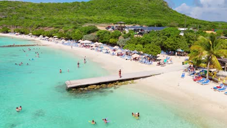 drone push in tilt down as tourists enjoy beautiful day at playa porto mari