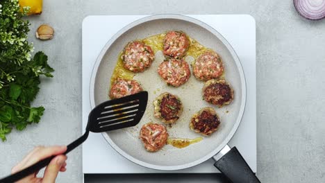 woman cooking meatballs on frying pan with oil