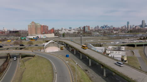 Seguimiento-Del-Autobús-Escolar-Amarillo-Que-Pasa-Por-Una-Larga-Rampa-De-Salida-Elevada-Del-Intercambio-De-Carreteras-En-La-Ciudad.-Boston,-Estados-Unidos