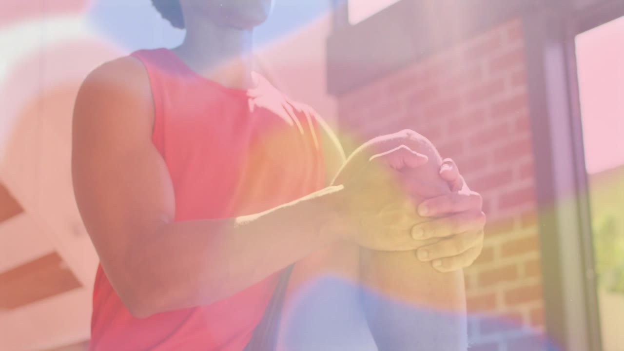 Man bringing right knee up and massaging knee post-workout while lens-flare moving across knee