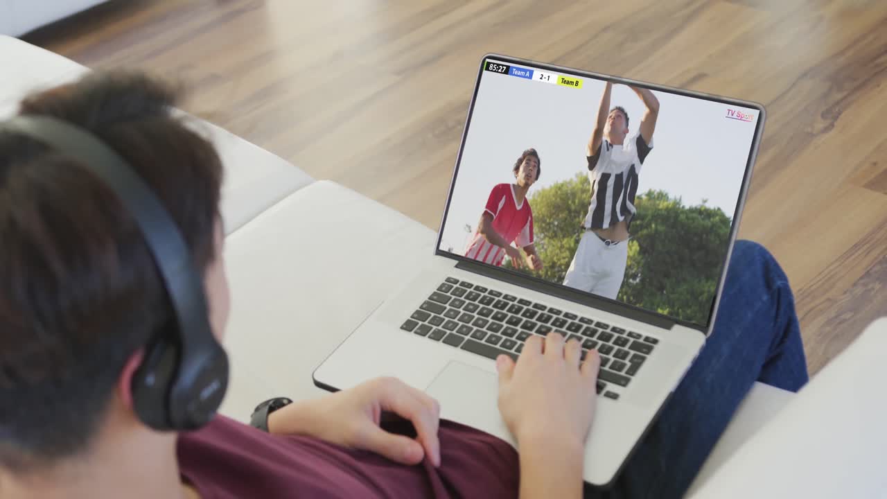 adolescente caucásico usando una computadora portátil con varios jugadores de fútbol masculino jugando un partido en la pantalla