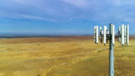 4K-Aufnahmen,-Die-Dicht-An-Einem-Mobilfunkmast-Vorbeifliegen,-Umgeben-Von-Goldenen-Hügeln-Und-Blauem-Himmel