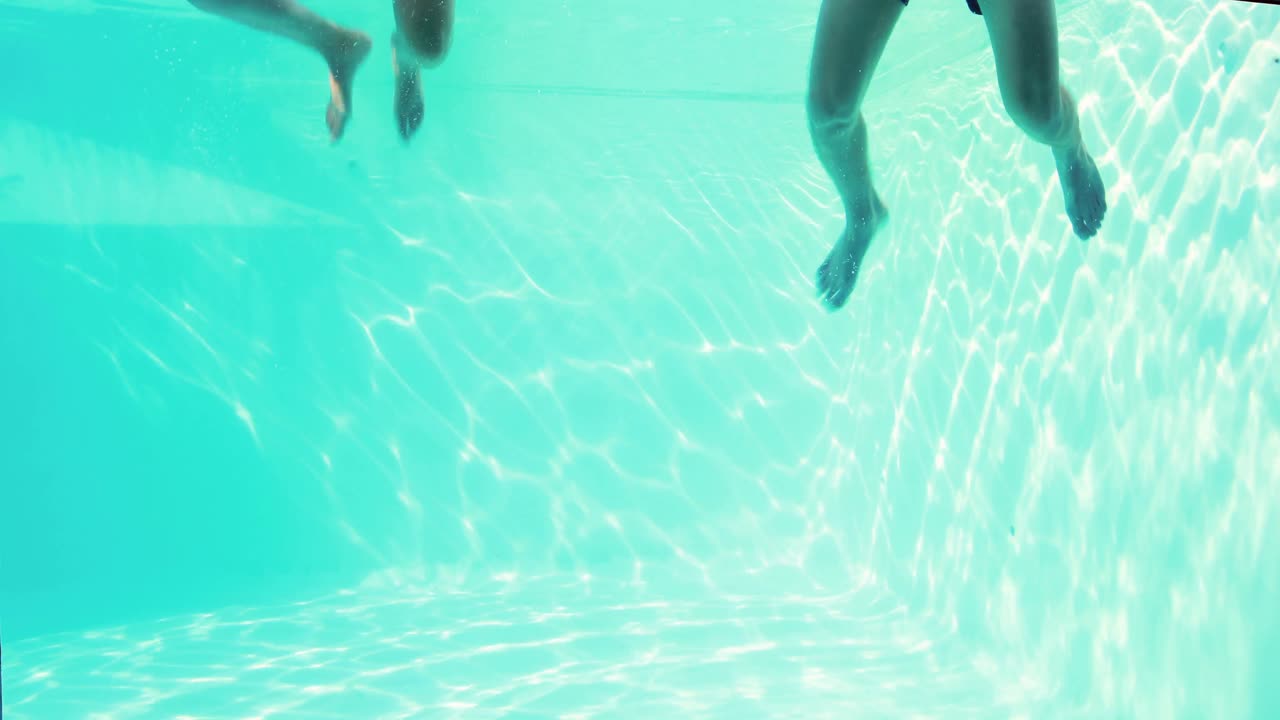 Pasangan bahagia melompat bersama di kolam renang sambil memakai snorkel