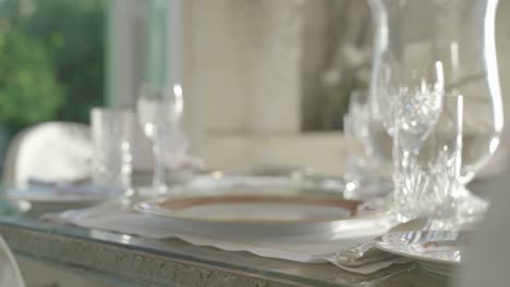 Waiter-setting-the-table-with-luxury-colorful-plate-on-decorated-table-with-glassware