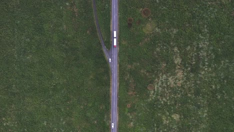 top down of cars traveling on straight road through green arctic meadow