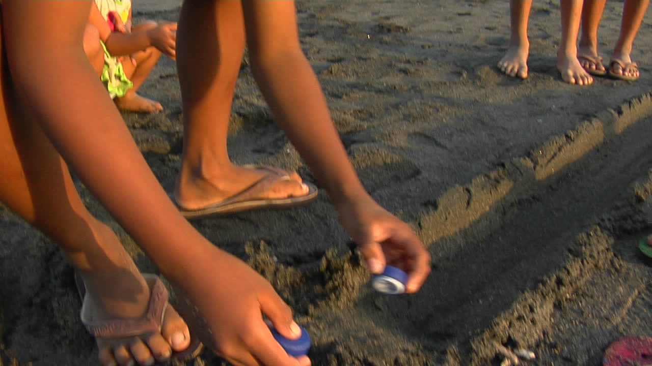 los niños de bali juegan un juego rodando tapas de botellas por la playa