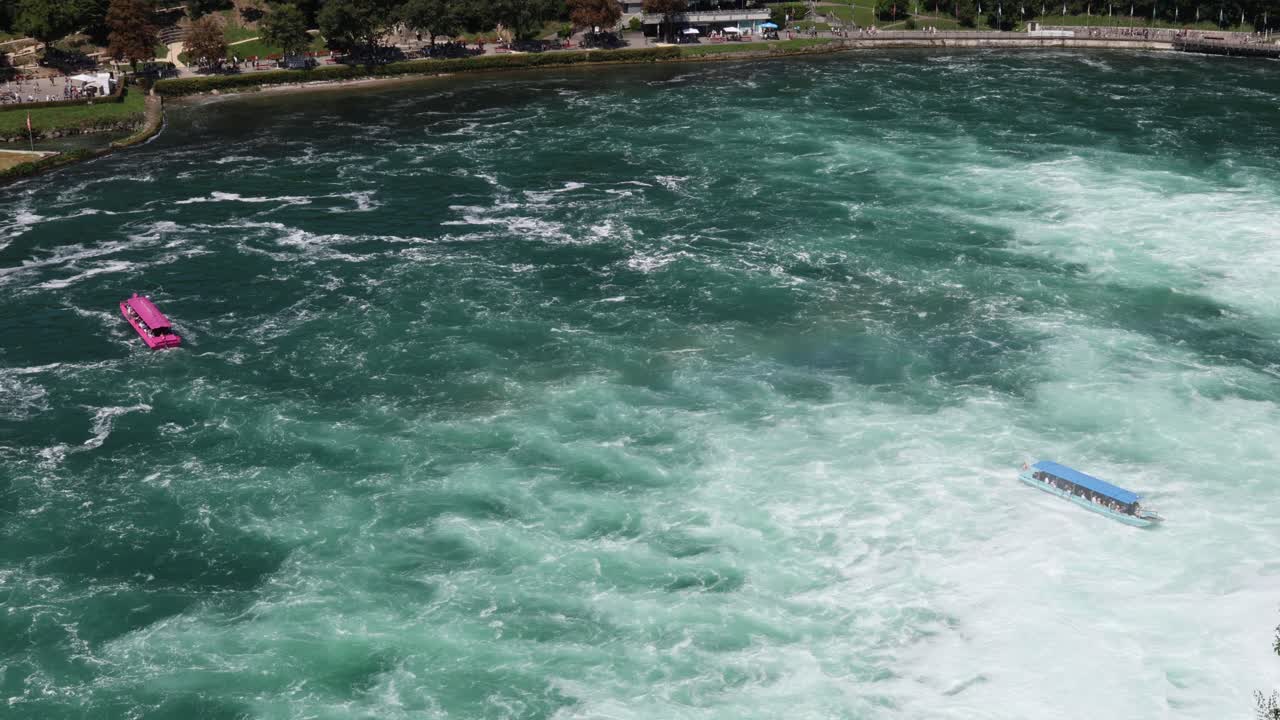 Tourist boats driving towards Rhine falls, aerial large waterfall