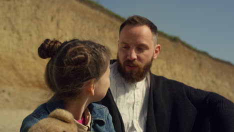 Joyful-family-posing-outside-at-seaside-beach.-Happy-dad-child-talk-on-nature.