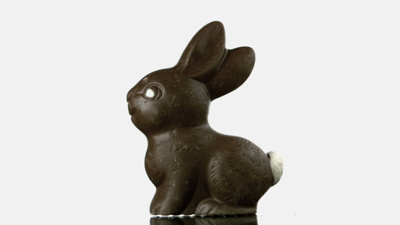Coelho de chocolate caindo e quicando em uma superfície branca