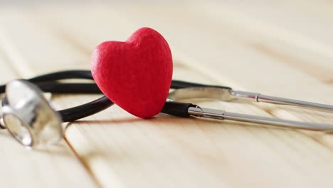 Video-of-stethoscope-with-red-heart-on-wooden-background-with-copy-space