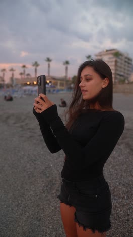 woman taking photo on the beach at sunset