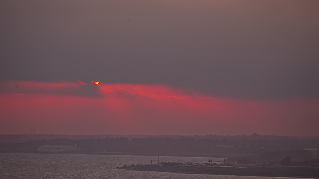 바다 위의 오렌지색 일몰은 어두운 구름으로  ⁇ 여 있습니다.