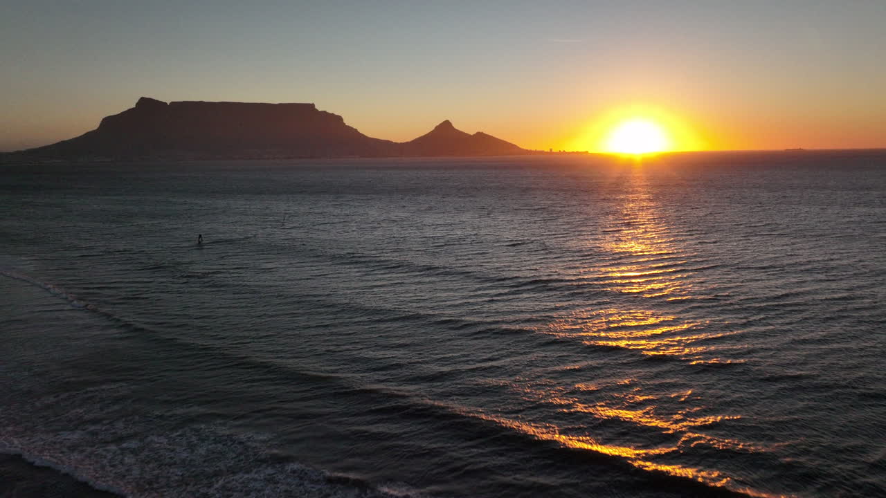 Cape Town South Africa windsurfers sailing windy surf wave Table Mountain drone aerial cinematic Lions Head sunset beach stunning mountain and ocean landscape orange gold sun on horizon forward pan up