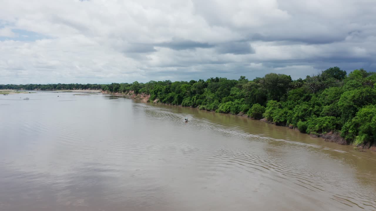 Aerial drone shot flying forward approaching a boat in a river in Selous, Tanzania. Cloudy sky