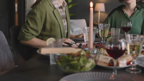 two adult women sitting at dinner table and talking together while having a family reunion at home