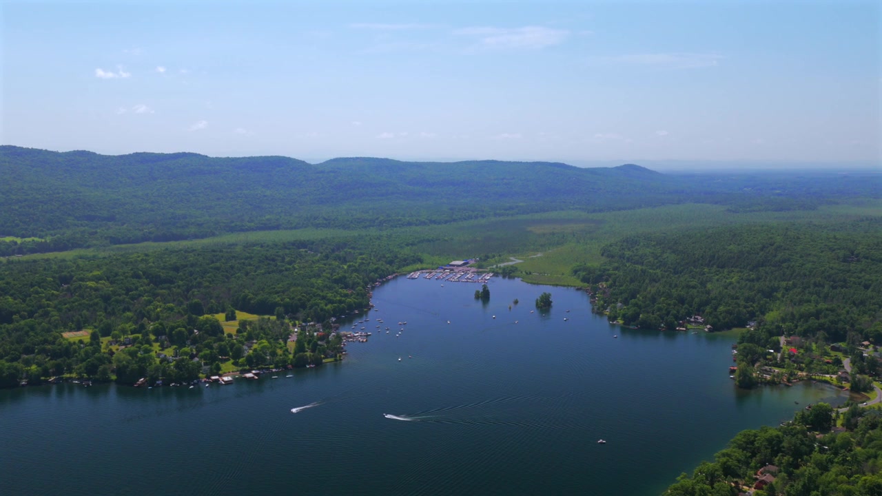 Lago George Monti Adirondack drone aereo Upstate New York Città di Lake George paesaggio barche molo vista porto Baia di Harris Assembly Point primavera estate mattina soleggiata cielo blu movimento circolare a destra
