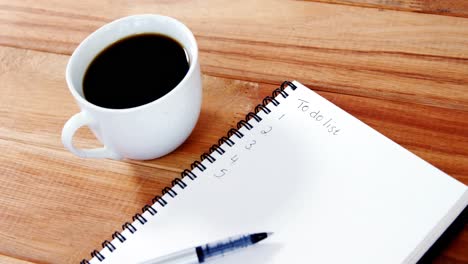 close-up of coffee cup with diary and pen