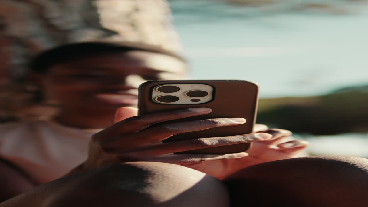 Close-up of Person's Hands Scrolling on Smartphone Outdoors in Sunlight