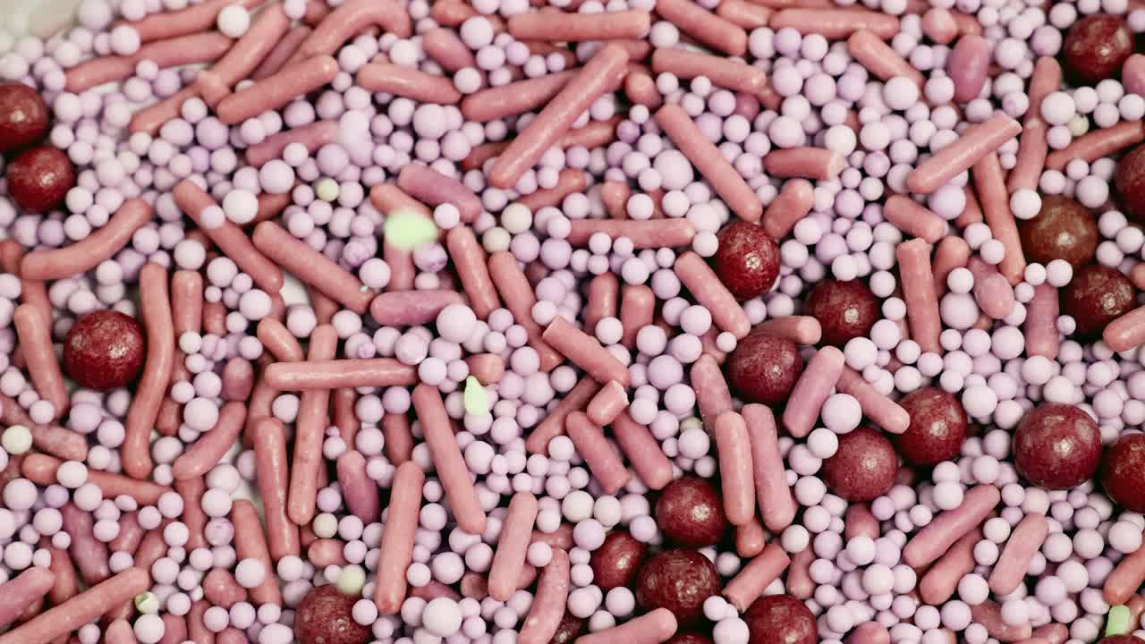 Vibrant candy sprinkles cascade onto a surface, creating a dynamic and colorful pattern. Bright lighting enhances the visual appeal