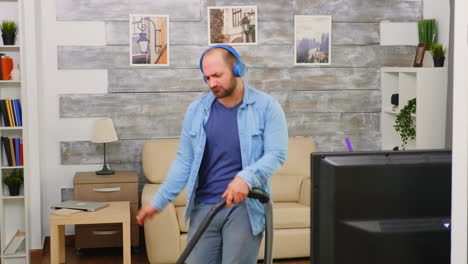 bold man with blue headphone vacuuming