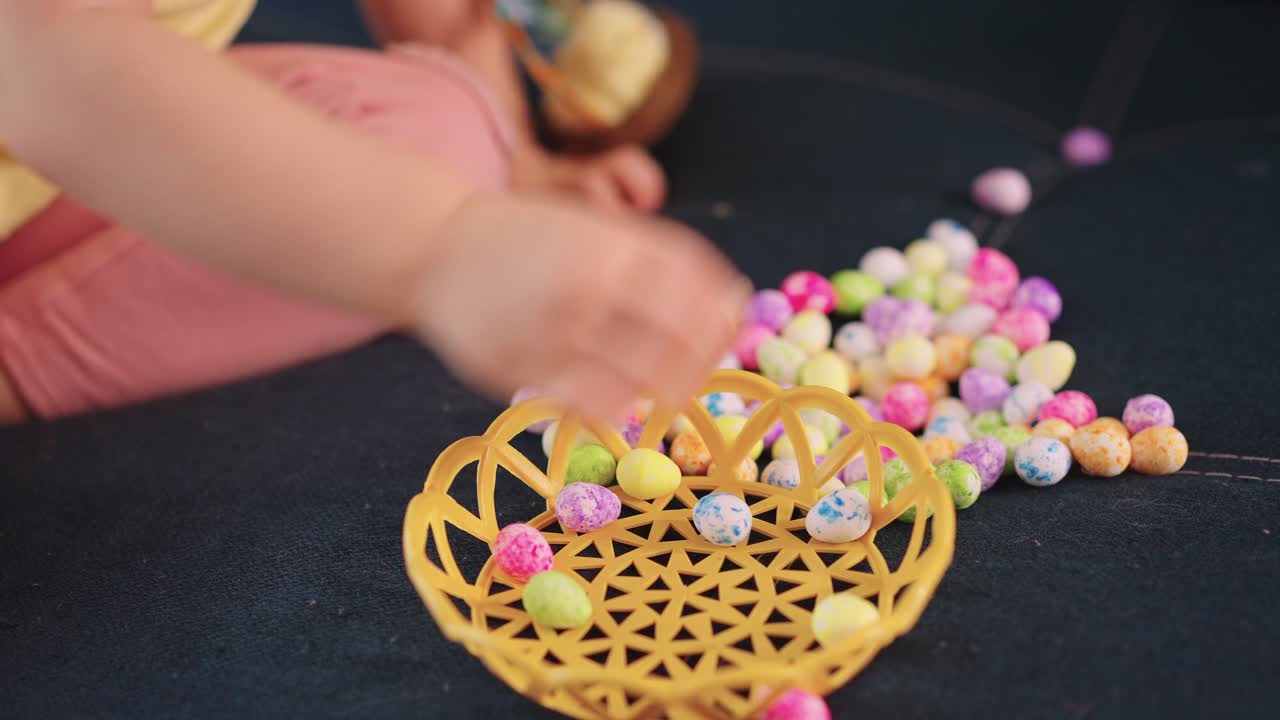 Child's Hand Playing with Colorful Easter Eggs and Yellow Basket