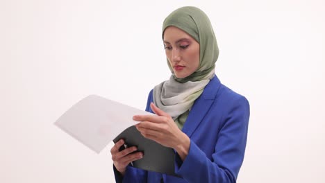 professional muslim businesswoman in hijab reviewing documents on a clipboard