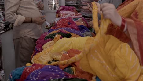 retails clothe seller showing different kind of indian traditional dress saree to customer at shop