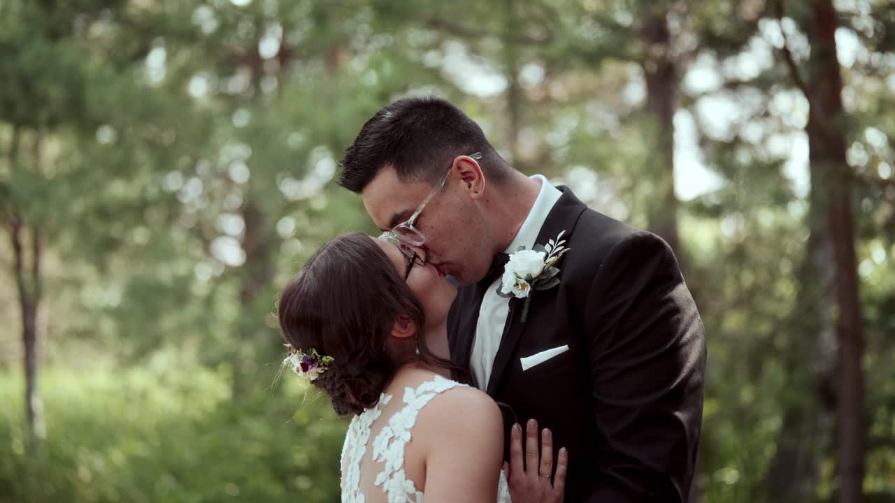 Handheld slow-motion close shot: bride hugs groom, looks up, then they kiss