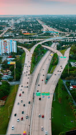 Flying above the wide-lane highway in Miami, Florida, USA. Green scenery of the city from top at sunset. Vertical video