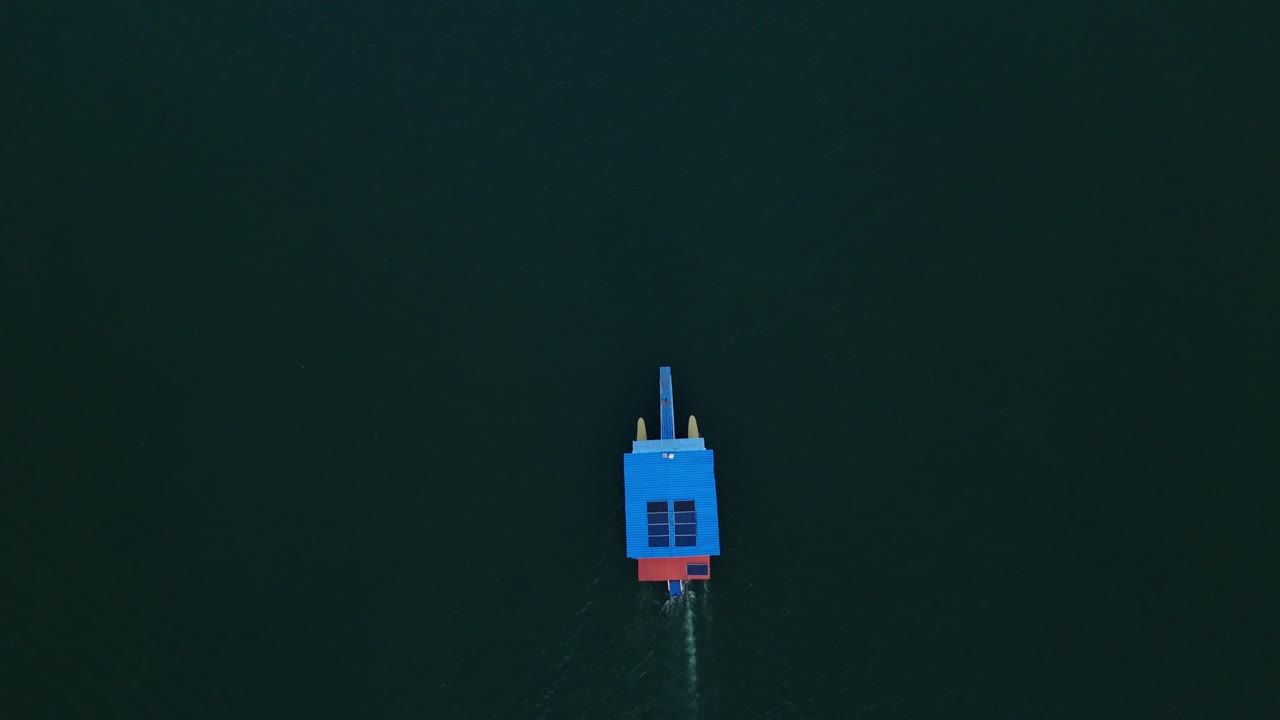 Top-down aerial view of a ferry navigating the blue waters of Hatillo Dam, Cotuí, Dominican Republic.