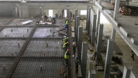 trabajadores de la construcción instalan barras de refuerzo de acero en un sitio de construcción industrial