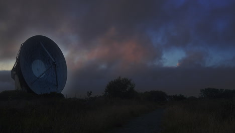 nubes de color puesta de sol moviéndose sobre una antena satelital, noche oscura - vista estática