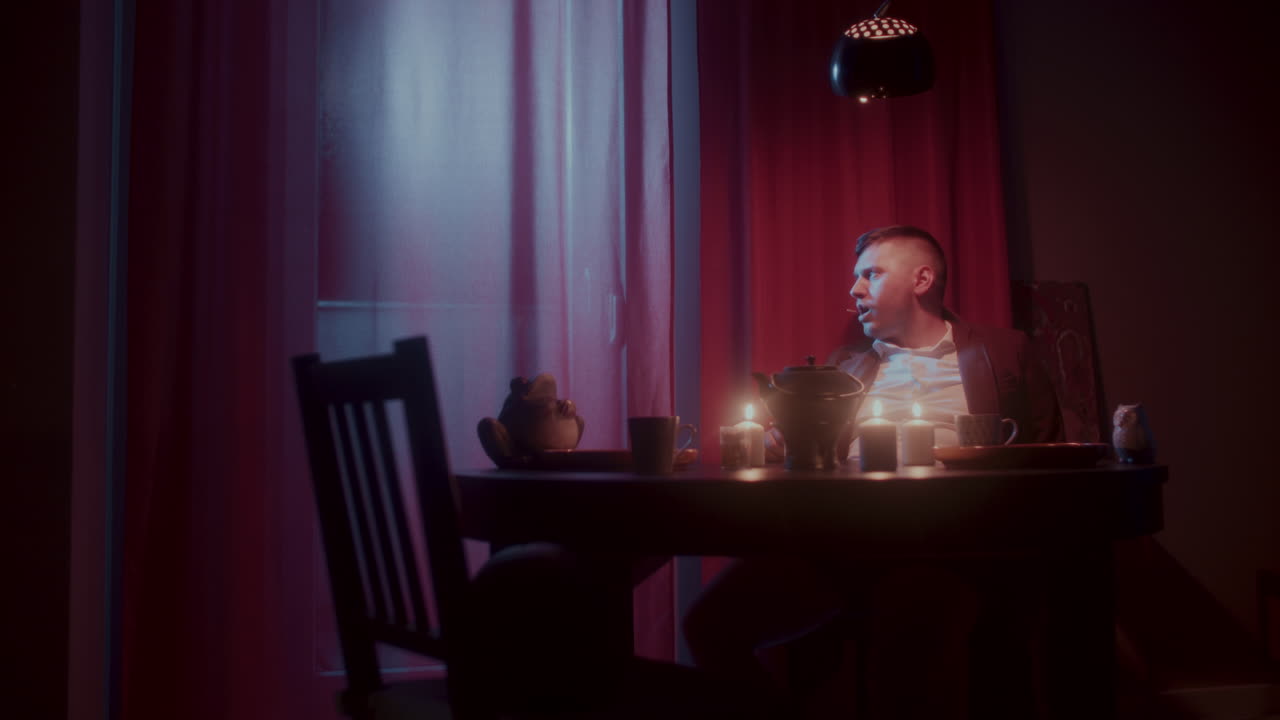 Man Sitting at a Table in a Dimly Lit Room