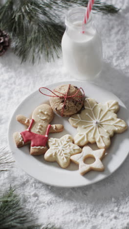 vertical video of bottle of milk, cookies with copy space on snow background