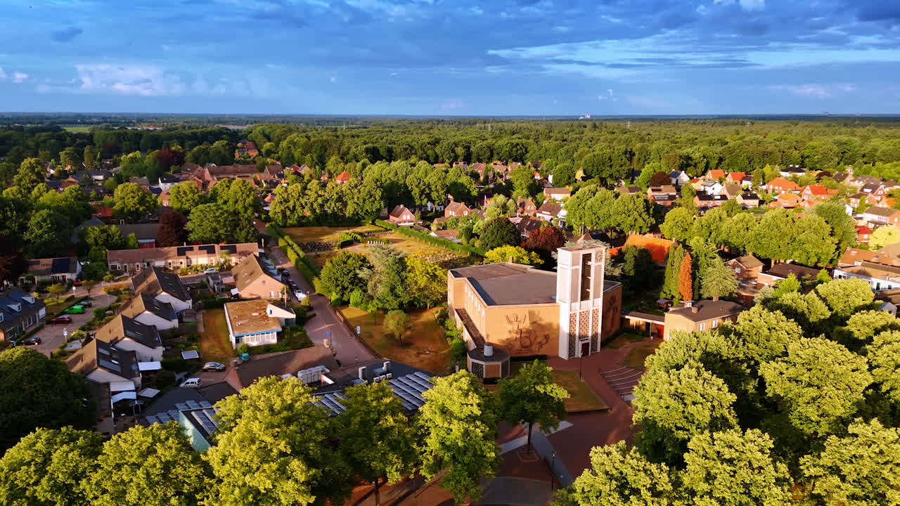 Colorful village with church. Aerial view of a charming village with greenery, homes, and a church under a clear blue sky
