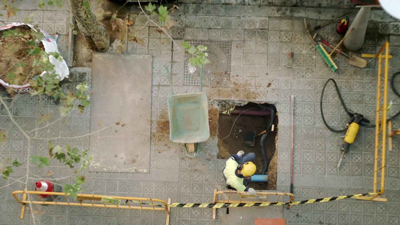 Vista dall'alto di un operaio edile che scava, pala e rompe il cemento su una strada di Barcellona