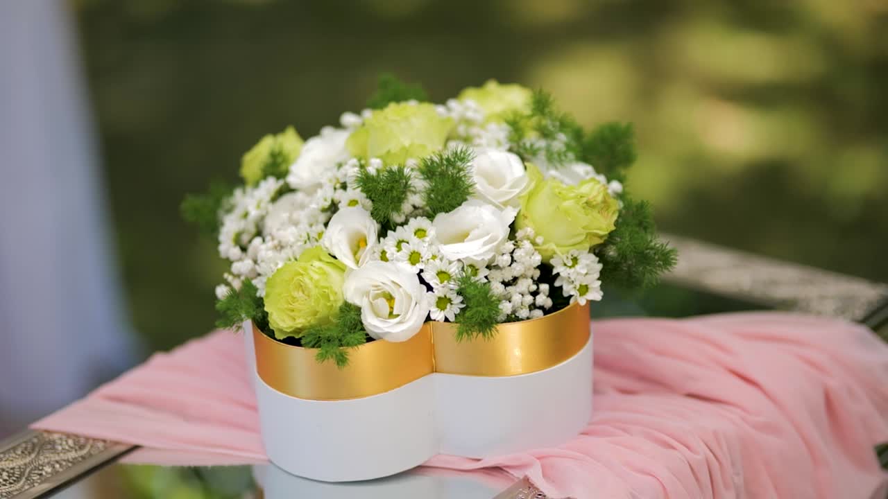 Elegante bouquet floreale verde e bianco su un tavolo all'aperto – Decorazione per matrimonio o battesimo con luce naturale.