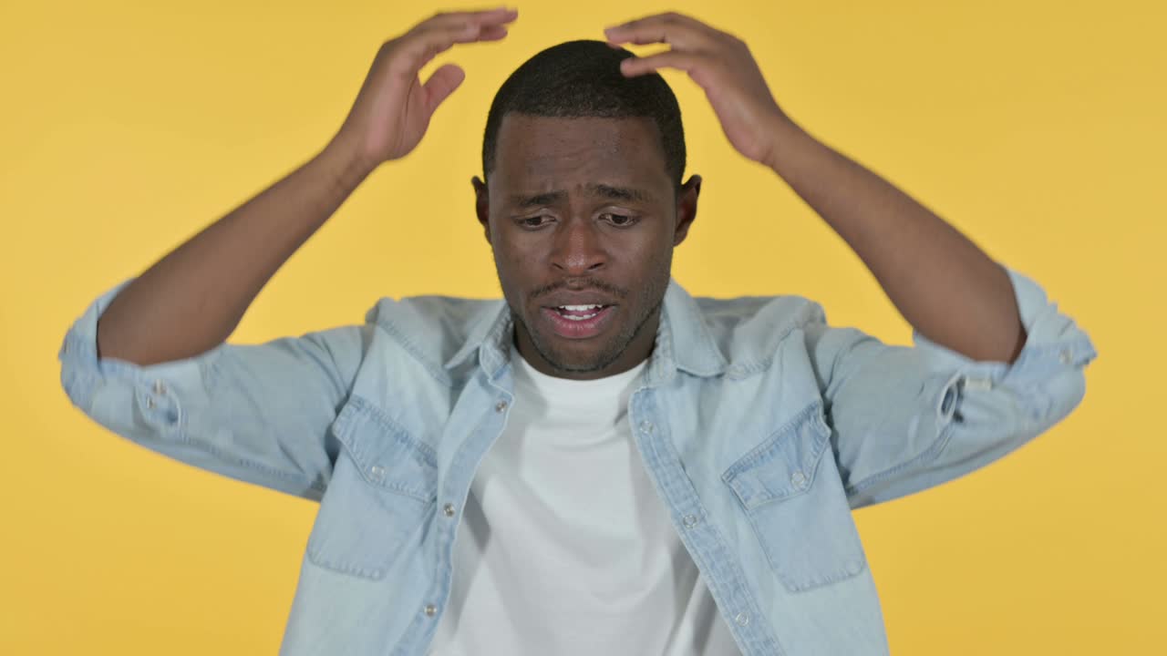 Young African Man Reacting to Loss, Yellow Background