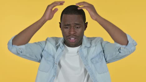 joven africano reaccionando a la pérdida, fondo amarillo