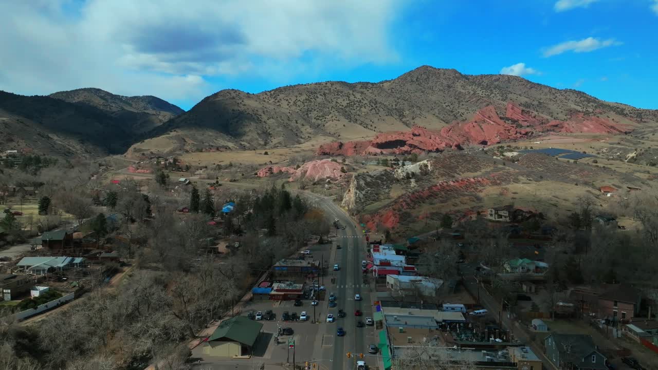 Winter downtown Main Street Morrison Colorado aerial drone Red Rocks Park and Amphitheater Mount Morrison Bear Creek sunny blue sky cloudy shaded traffic car driving backwards motion