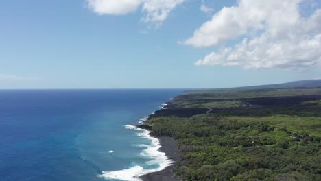 wide aerial panning shot of a newly formed black sand beach on the big island of hawaii