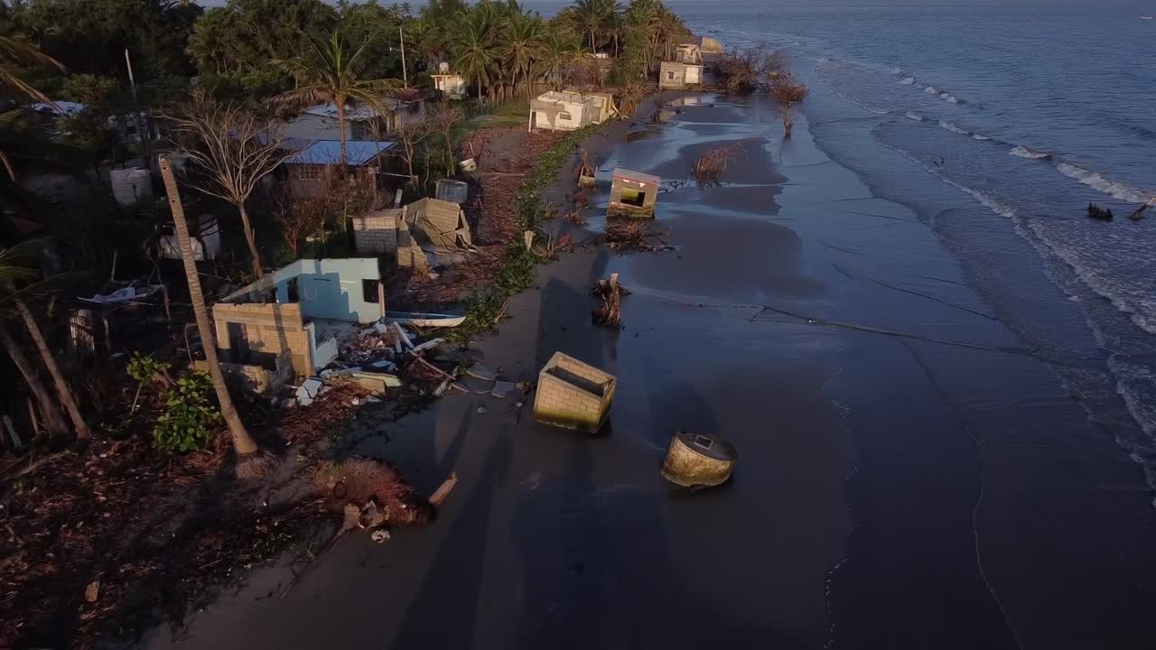 Carrellata, costa e piccole case colpite dall'innalzamento del livello dell'oceano a causa del cambiamento climatico.