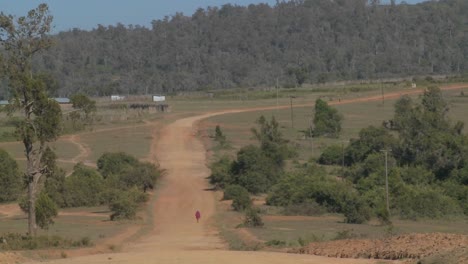 A-man-walks-in-the-distance-on-a-lonely-dusty-dirt-road-in-Africa