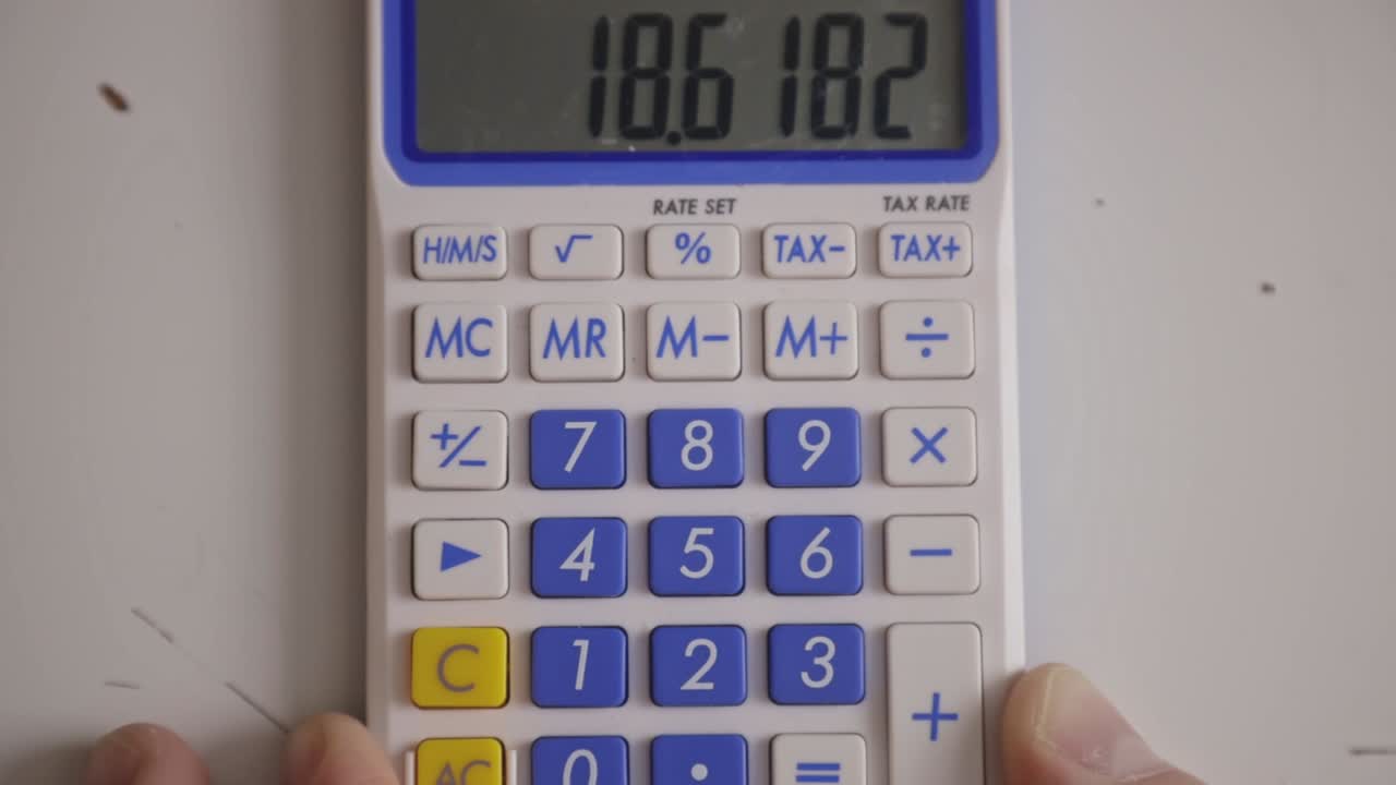 el dedo presiona números y multiplica usando la calculadora en la mesa