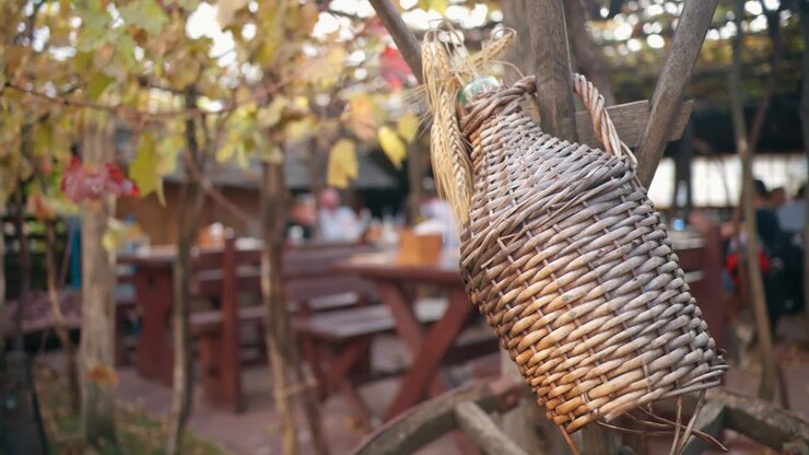 Nærbilde av tradisjonell vinflaske i en vingård-restaurant med bord og folk i en landsby, Moldova