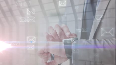 animación de iconos de correo electrónico contra la sección media del hombre de negocios caucásico comprobando el reloj inteligente